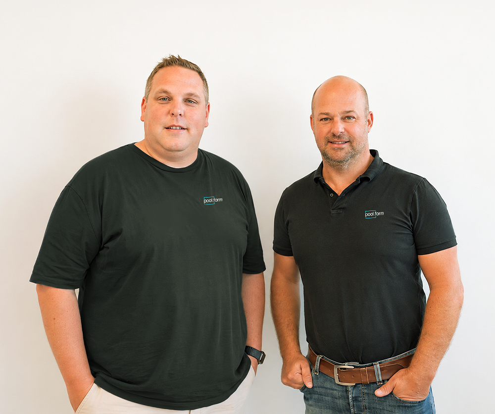 Mathias Ausserbrunner & Mario Berchtold von poolform in schwarzen Poloshirts stehen nebeneinander und lächeln in die Kamera.